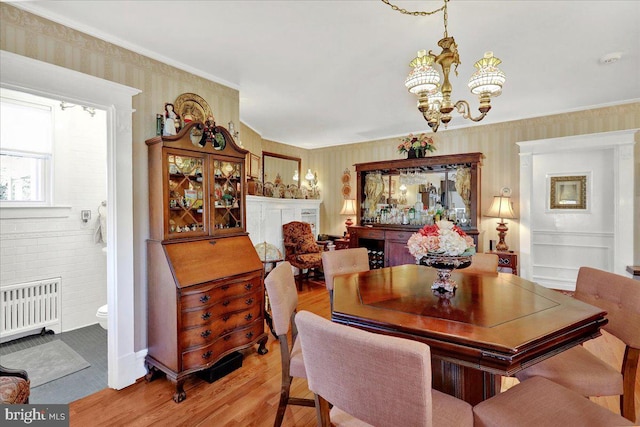 dining room featuring light wood-style flooring, radiator, a chandelier, and wallpapered walls