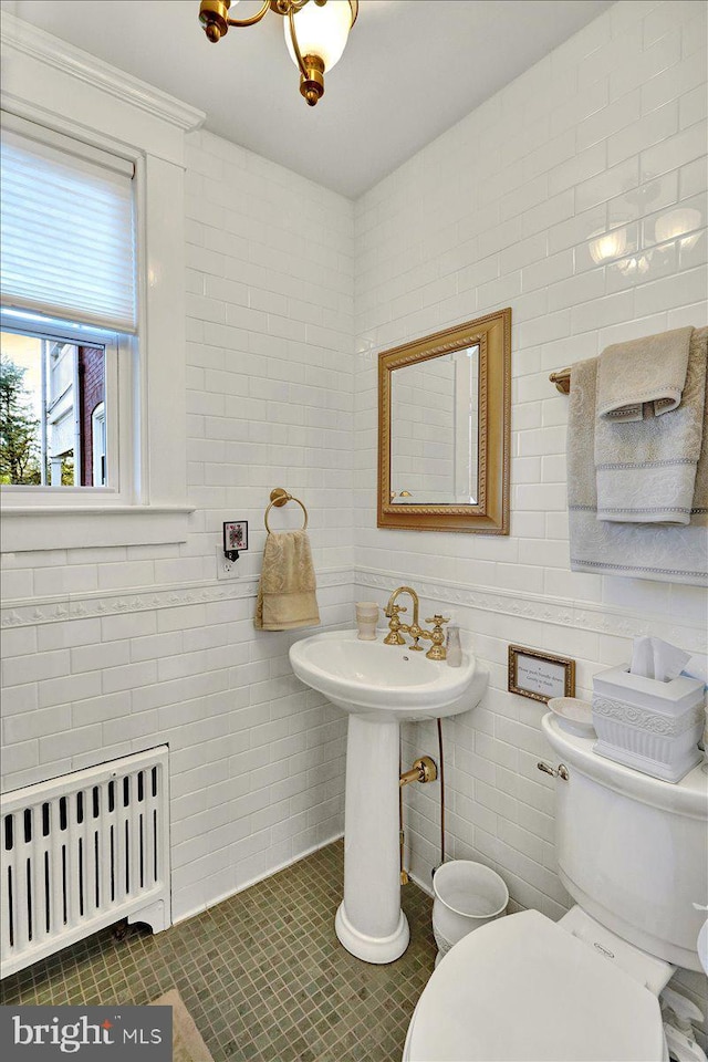 bathroom with tile patterned floors, toilet, radiator heating unit, and tile walls