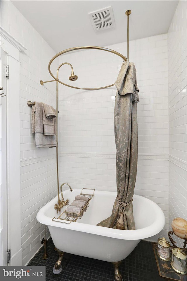 full bath featuring tile walls, a freestanding tub, visible vents, and tile patterned floors