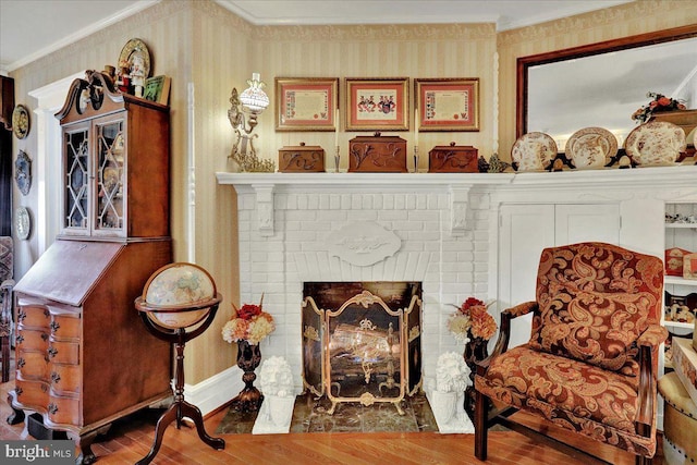 sitting room featuring wallpapered walls, crown molding, and wood finished floors