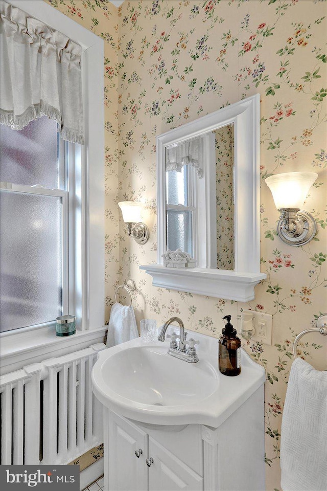 bathroom featuring wallpapered walls, radiator heating unit, and vanity