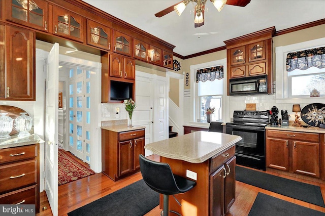 kitchen with tasteful backsplash, light wood finished floors, ceiling fan, light countertops, and black appliances