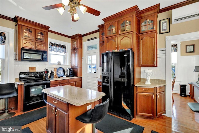 kitchen featuring an AC wall unit, black appliances, light countertops, and light wood-style floors