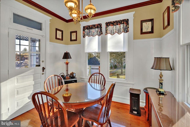 dining room featuring a decorative wall, a notable chandelier, light wood-type flooring, and ornamental molding