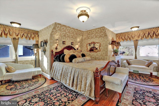 bedroom featuring baseboards, wood finished floors, and wallpapered walls