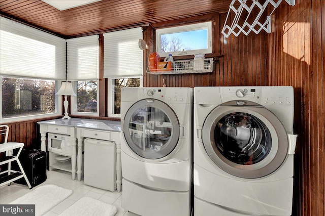 laundry area with wooden walls, light tile patterned floors, wood ceiling, laundry area, and washing machine and clothes dryer