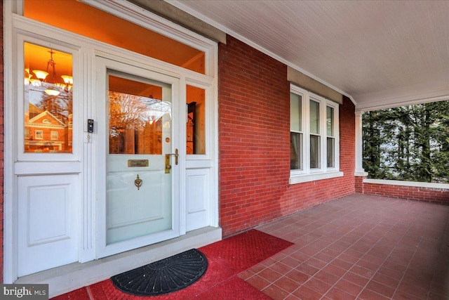 doorway to property featuring brick siding and a porch