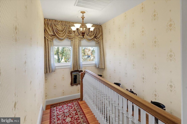 interior space featuring a chandelier, wallpapered walls, baseboards, and wood finished floors