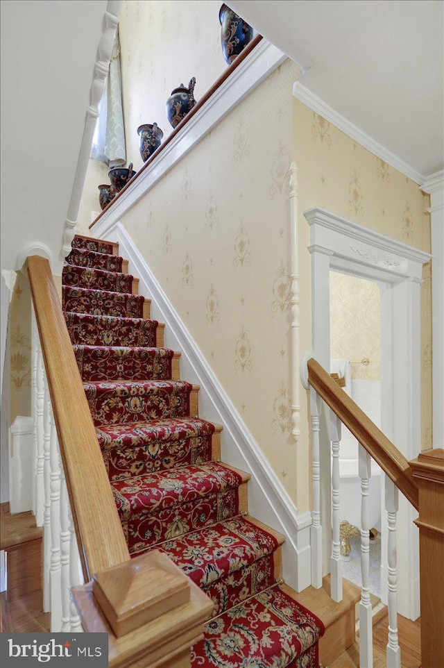 stairs featuring wallpapered walls and crown molding