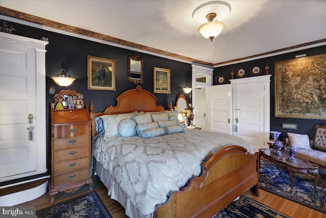 bedroom featuring ornamental molding and wood finished floors