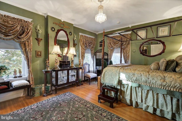 bedroom with crown molding, an inviting chandelier, and wood finished floors