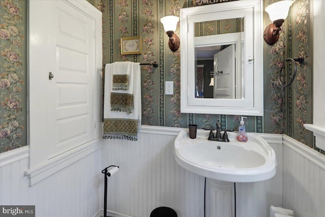 bathroom with a wainscoted wall and wallpapered walls