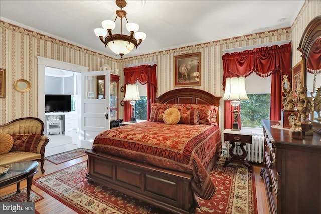 bedroom featuring a notable chandelier, radiator, wood finished floors, and wallpapered walls