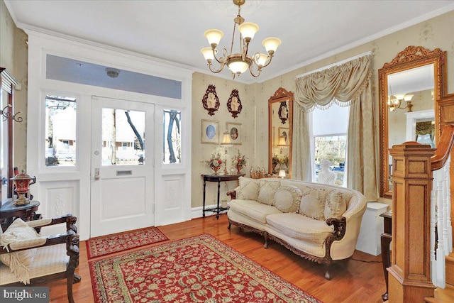 entrance foyer with a notable chandelier, crown molding, and wood finished floors