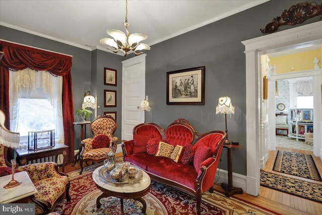 sitting room with a notable chandelier, wood finished floors, baseboards, and ornamental molding