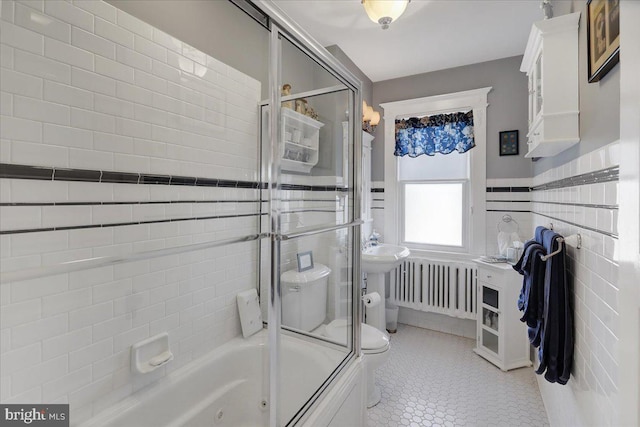 full bathroom featuring a wainscoted wall, radiator heating unit, tile patterned flooring, tile walls, and toilet