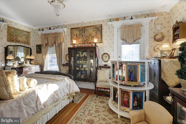 bedroom with wood finished floors and wallpapered walls