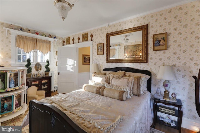 bedroom featuring wallpapered walls, crown molding, and wainscoting