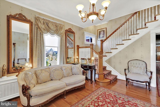 living area with stairway, wood finished floors, a chandelier, and wallpapered walls