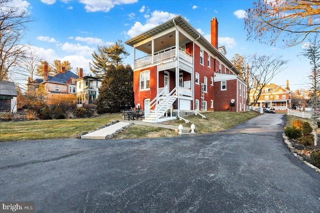 view of front facade featuring brick siding, a balcony, and a front yard