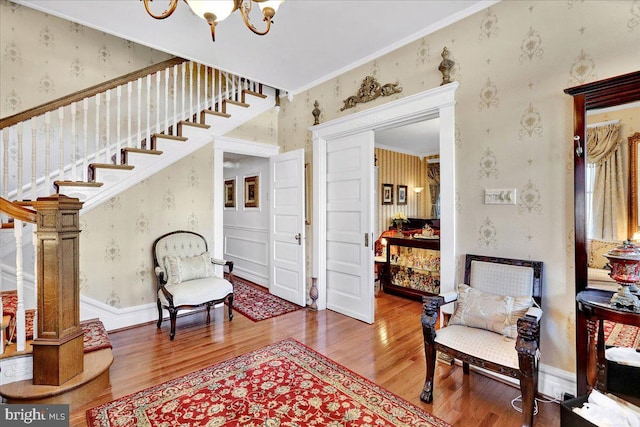 sitting room featuring stairway, wallpapered walls, baseboards, and wood finished floors