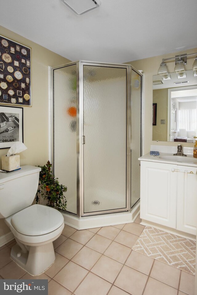 bathroom with vanity, tile patterned floors, toilet, and a stall shower