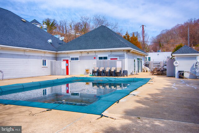 pool with a storage shed, an outbuilding, fence, and a patio