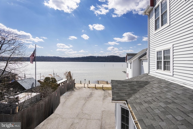 view of patio with fence and a water view