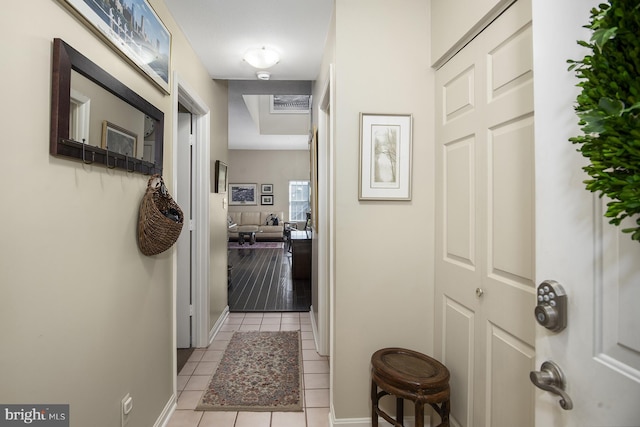 hall featuring light tile patterned floors and baseboards