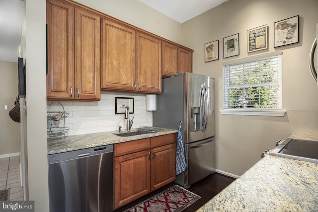 kitchen featuring brown cabinetry, backsplash, appliances with stainless steel finishes, and a sink