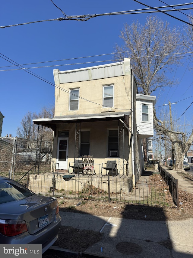 view of front facade featuring stucco siding, a porch, a fenced front yard, and a gate