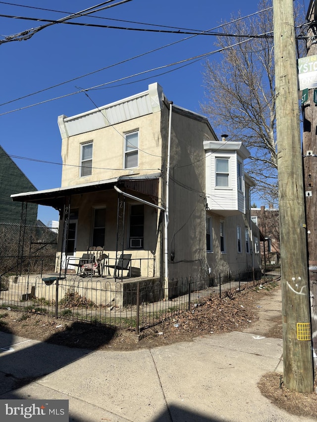 view of front facade with a fenced front yard, stucco siding, and a porch