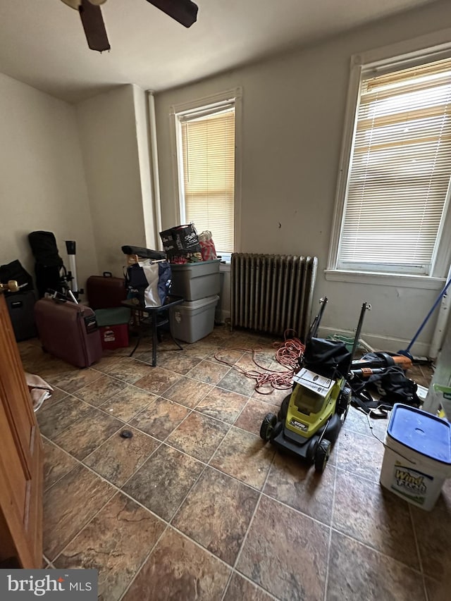 interior space with a ceiling fan and radiator heating unit