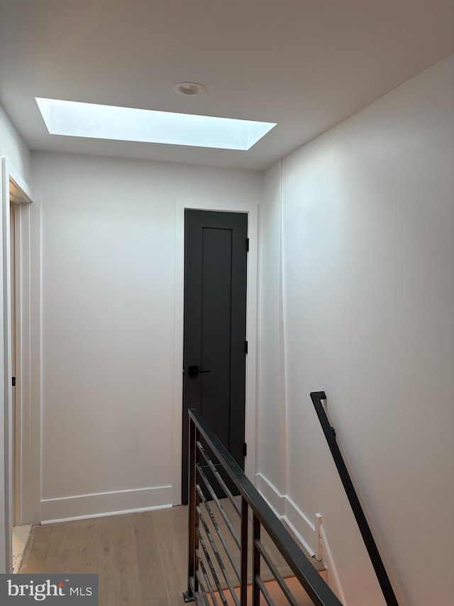 corridor featuring an upstairs landing, light wood-type flooring, and baseboards