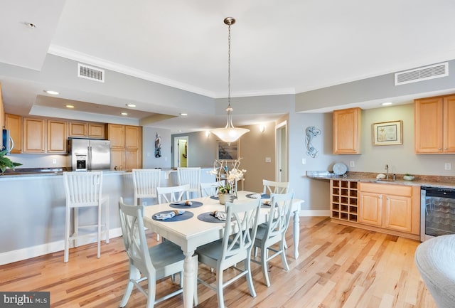 dining area with visible vents, light wood-style flooring, baseboards, and ornamental molding