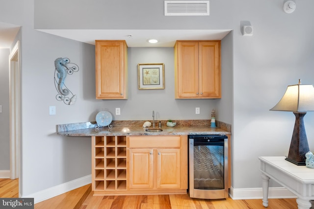 bar featuring light wood-style floors, beverage cooler, visible vents, and baseboards