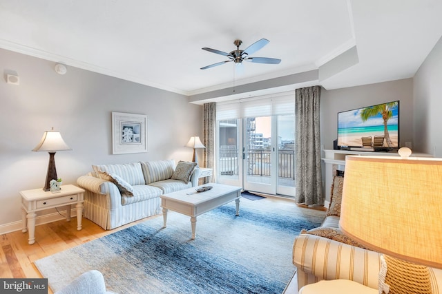 living area featuring crown molding, wood finished floors, baseboards, and ceiling fan