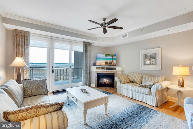 living room featuring visible vents, wood finished floors, baseboards, ceiling fan, and a tile fireplace