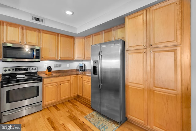 kitchen with light brown cabinetry, visible vents, light wood finished floors, and appliances with stainless steel finishes