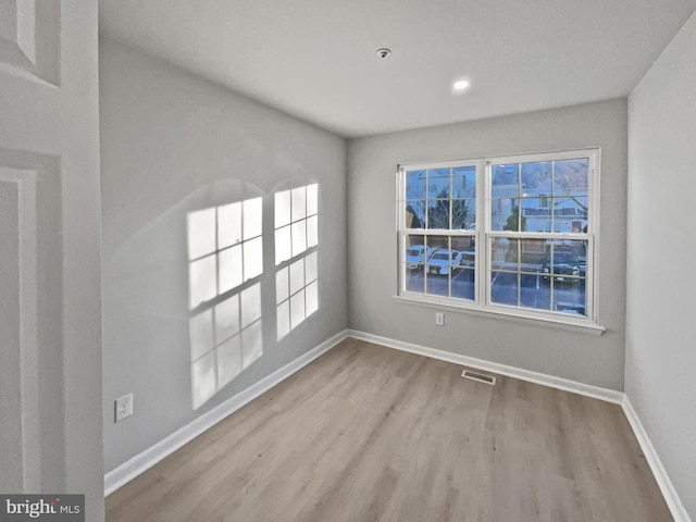 empty room with wood finished floors, baseboards, and visible vents