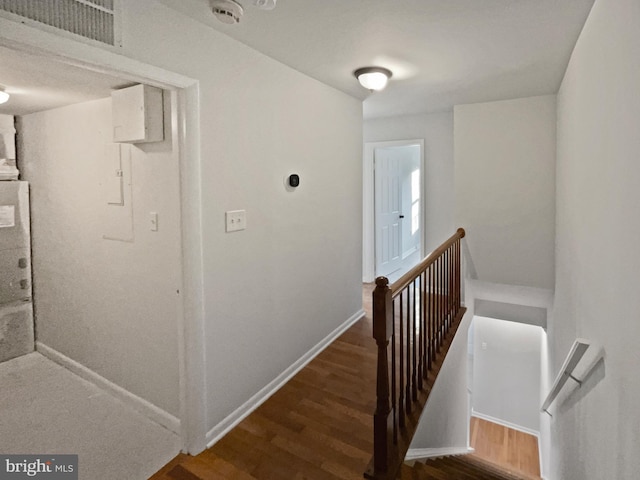 hallway featuring an upstairs landing, baseboards, and wood finished floors