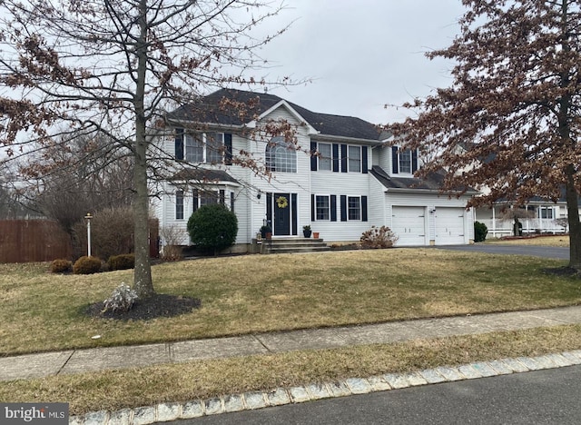 colonial-style house featuring a front yard, fence, and aphalt driveway