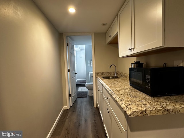 kitchen with white cabinets, baseboards, black microwave, and a sink