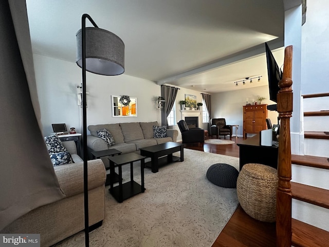 living area with stairway, a fireplace, and wood finished floors