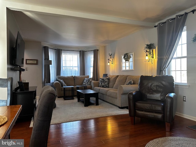 living area with beamed ceiling, wood finished floors, and baseboards