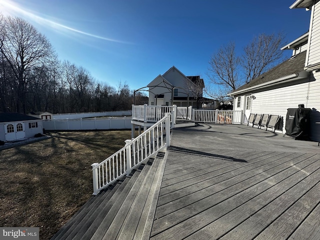 wooden terrace featuring an outdoor structure, fence, and a lawn