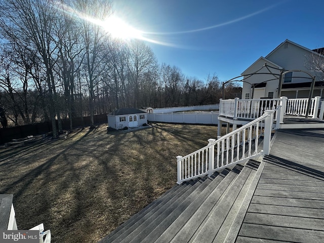 wooden terrace with an outdoor structure, a yard, and fence