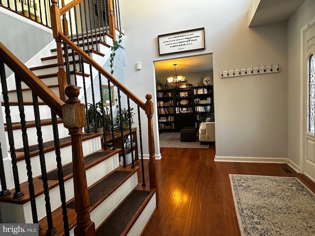 entryway with a chandelier, stairway, baseboards, and wood finished floors