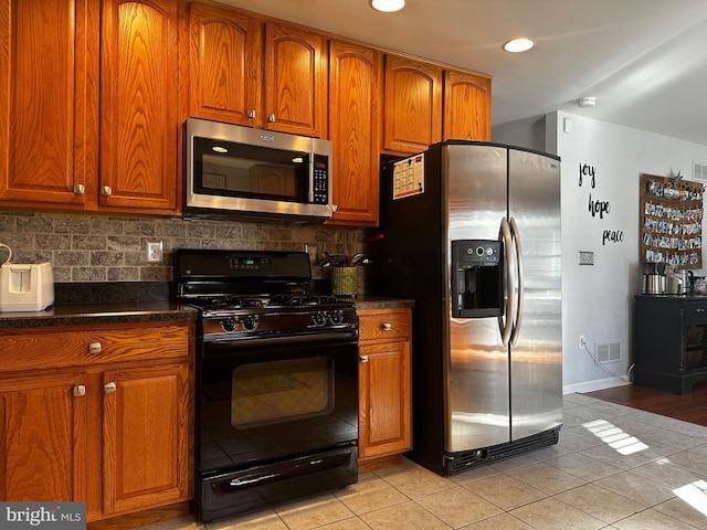 kitchen with dark countertops, tasteful backsplash, visible vents, and appliances with stainless steel finishes