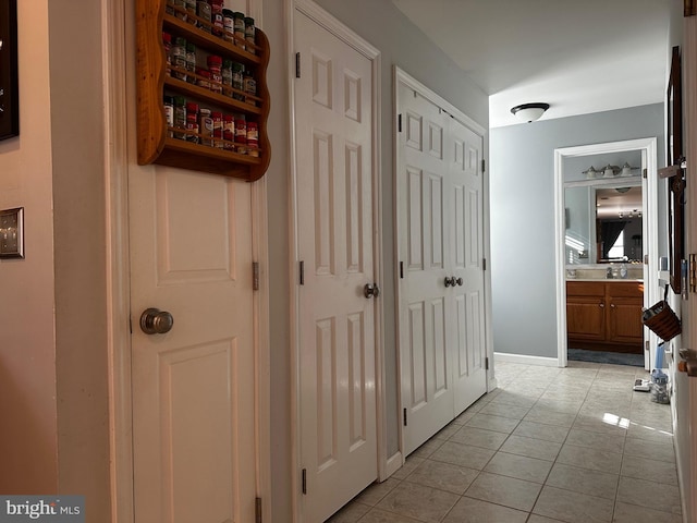 hall with light tile patterned floors, baseboards, and a sink